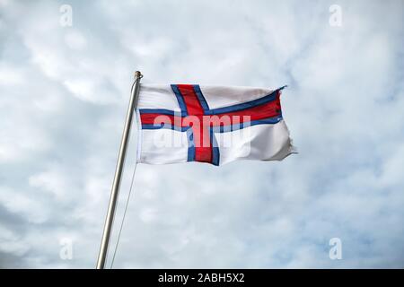 Flagge der Färöer winken gegen einen bewölkten Himmel Stockfoto