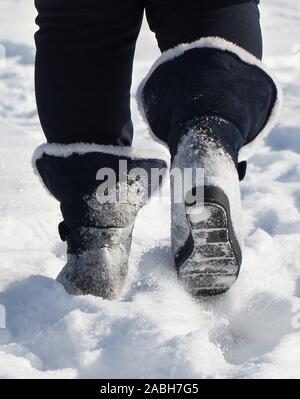 Schritte im Schnee mit Stiefeln Beine einer Frau. Stockfoto