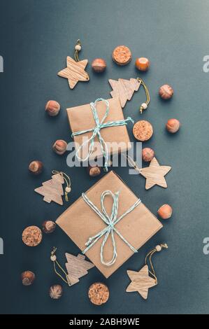 Vertikaler Weihnachten Dekoration im Stil von hygge Geschenkboxen auf dunkelgrünem Hintergrund. Ansicht von oben. Stockfoto