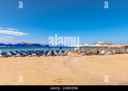 Naxos, Griechenland - 22. Mai 2017: Sonnenliegen mit Sonnenschirmen am Strand von Agios Georgios, sehr beliebten Ferienort auf der Insel Naxos, Griechenland. Stockfoto