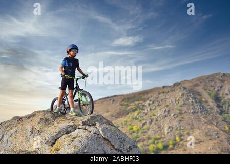 Glückliches Kind Junge von 7 Jahren Spaß im Herbst Park mit dem Fahrrad auf schönen Herbst Tag. Aktives kind Fahrradhelm tragen Stockfoto