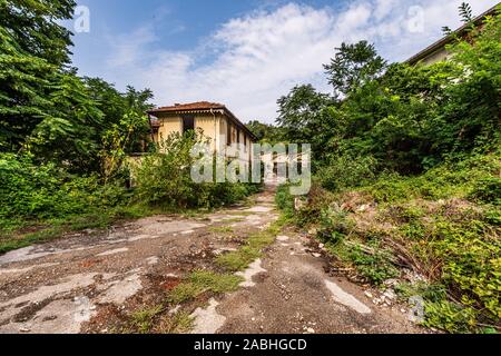 Holprige Straße, die zu einem großen verlassenen industriellen Komplex führt, eine Landschaft von Urban exploration auch bekannt als urbex Stockfoto