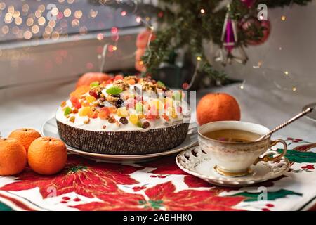 Weihnachten und Silvester traditionelle weihnachtliche Gerichte. Pannetone, Stollen, Kuchen mit kandierten Nüssen, Kaffee in einer Tasse auf einem festlichen Tischdecke mit poins Stockfoto