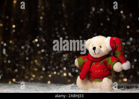 Weihnachten Ansicht der Teddybär in rot grünen Pullover und Mütze auf dunklem Hintergrund mit Silber und Gold. Urlaub Konzept mit Kopie Raum Stockfoto
