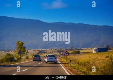 Ein Auto überholen Linie der Autos, während ein Lkw kommt von den entgegengesetzten Weg auf der Straße zwei Art und Weise mit der Landschaft von Gorski Kotar in Kroatien. Stockfoto