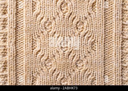 Beige Pullover Stoff Textur mit Anschlusslitzen. Beige gestrickter Hintergrund. Stockfoto
