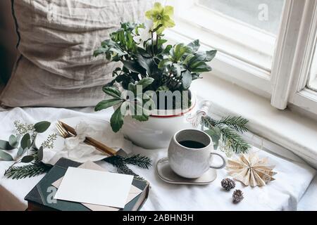 Winter Frühstück noch leben Szene. Moody Weihnachten festlich gedeckten Tisch mit goldenem Besteck, Tasse Kaffee, Grußkarte, Eukalyptus und Tannenbaum Stockfoto