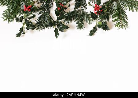 Weihnachten Floral frame, Web Banner. Grenze der roten Stechpalme Beeren und Grüne Tanne Filialen auf weißem Hintergrund. Winter natürliche Stockfoto