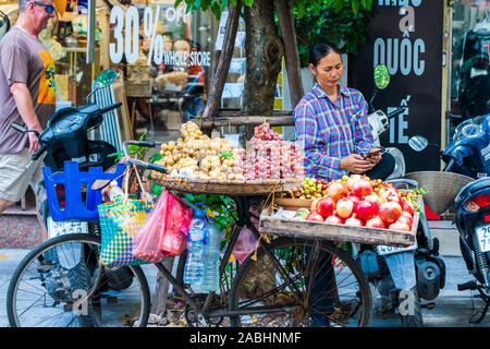 Hanoi, Vietnam - 11. Oktober 2019: ein Street Food Verkäufer nehmen Obst um auf seinem Fahrrad zu verkaufen in der Stadt Stockfoto