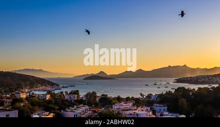 Farbenfrohen Sonnenuntergang in der schönen Bucht der Ägäis mit Inseln, Berge, Boote und Vögel in den Himmel. Sommerurlaub Konzept und Reisen Stockfoto