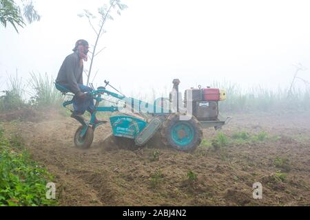 Bangladesch - Januar 06, 2014: An einem nebligen Morgen im Winter ist ein betriebsinhaber Pflügen sein Land mit einem 2-Rad Traktor bei Ranisankail, Thakurgaon. Stockfoto