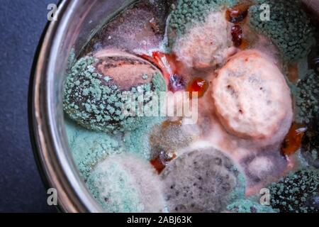 Nahaufnahme von Schimmel auf schwarze Oliven in einer Glasflasche hinterlegt. Stockfoto