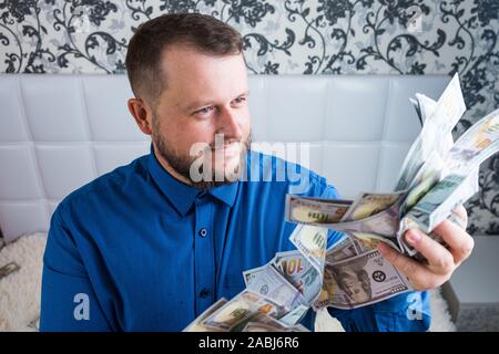 Mann hält in der Hand eine große Menge Geld. Ein Mann erfreut sich großer Reichtum, eine Menge von Banknoten der Dollar. Stockfoto