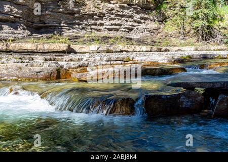 Schönen fließenden Bergbach entlang einer felsigen Flussbett, mit schönen Bäumen und Felsen gesäumt. Stockfoto