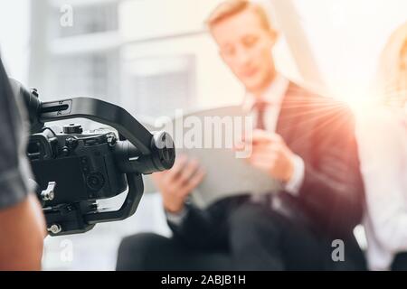 Videofilmer professionelle Aufnahmen Videos aufnehmen mit langer Gimbal Kamera Stabilisator für Anti Shake Device Technology in Geschäftsmann Szene. Stockfoto