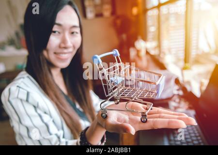 Business Mädchen lächelnd mit Warenkorb in ihrer Hand für online kaufen und verkaufen. Stockfoto