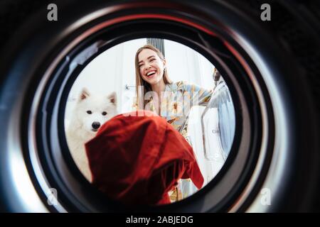 Junge Frau zu Hause setzt das Kleid im Trockner. Stockfoto