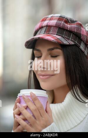 Gerne dunkelhaarige Frau riechen ihre köstlichen Kaffee Stockfoto