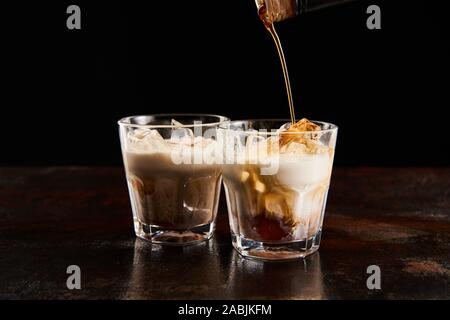 Kaffeelikör brütete in Gläser mit Eiswürfeln isoliert auf Schwarz Stockfoto