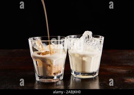 Kaffeelikör brütete in Gläser mit Eiswürfeln isoliert auf Schwarz Stockfoto