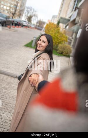 Freudige brünette Frau, die ihre Ehemänner Hand Stockfoto