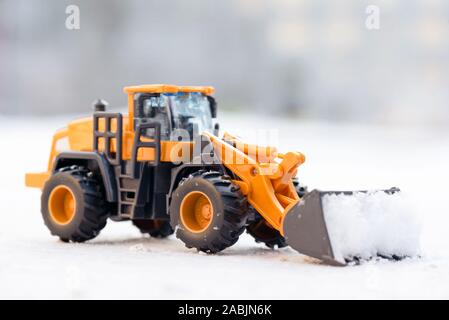 Spielzeug Traktor Reinigung der Straße von Schnee Konzept. Stockfoto