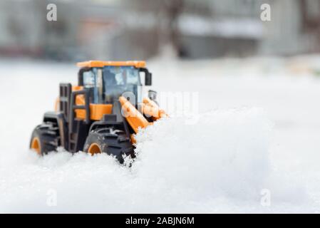 Spielzeug Traktor Reinigung der Straße von Schnee Konzept. Stockfoto