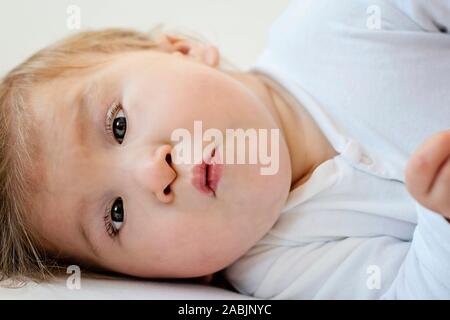 Porträt eines Babys mit Zerebralparese liegend auf dem Bett. Besondere Bedürfnisse Kind. Behinderte baby boy Close-up. Behinderten Kindes. Stockfoto