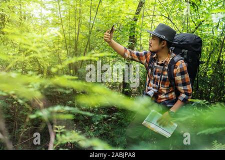 Mann Reisender mit Rucksack mit Smartphone mit einem selfie im natürlichen Wald Stockfoto