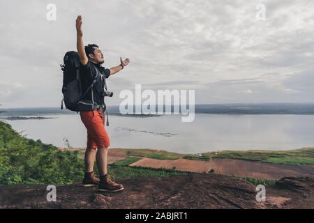 Fröhliche Wanderer mann Geste erhobenen Armen am Rand der Klippe, an der Spitze der Rock Mountain Stockfoto