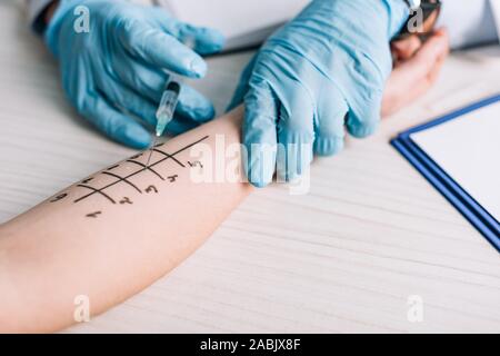 7/8-Ansicht von allergist in Latex Handschuhe halten Sie die Spritze in der Nähe der Frau in Klinik Stockfoto