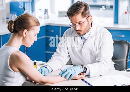 Selektiver Fokus der stattlichen allergist Holding Herrscher in der Nähe der markierten Hand der Frau Stockfoto