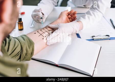 7/8-Ansicht von allergist halten Sie die Spritze in der Nähe der Mann mit der Hand Stockfoto