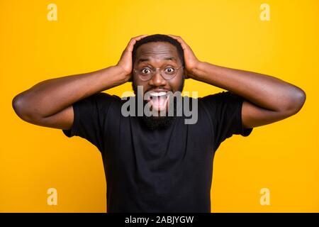 Foto fröhliche, positive Lustig niedlich schwarzer Mann überglücklich über ermäßigte Shopping Mall packte seinen Kopf mit den Händen im t-shirt isoliert lebendige Stockfoto