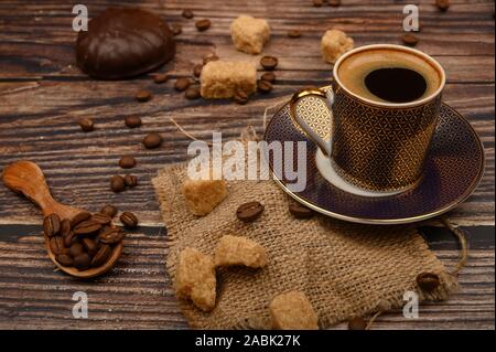 Tasse Kaffee, brauner Zucker, Kaffeebohnen, Marshmallows in Schokolade auf Holz- Hintergrund Stockfoto
