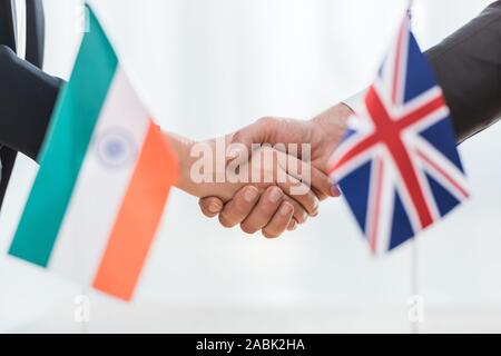 7/8-Ansicht von Diplomaten Händeschütteln in der Nähe der Flagge von Indien und Großbritannien Stockfoto