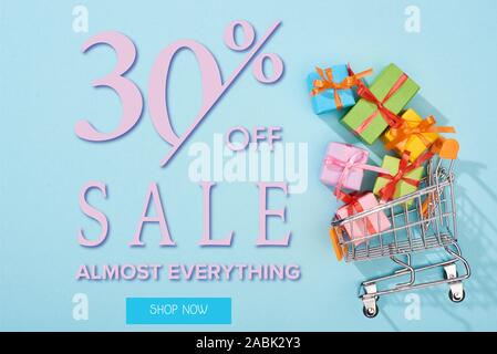 Blick von oben auf die festliche eingepackten Geschenke im Warenkorb auf blauem Hintergrund mit 30 Prozent weg vom Verkauf Abbildung: Stockfoto