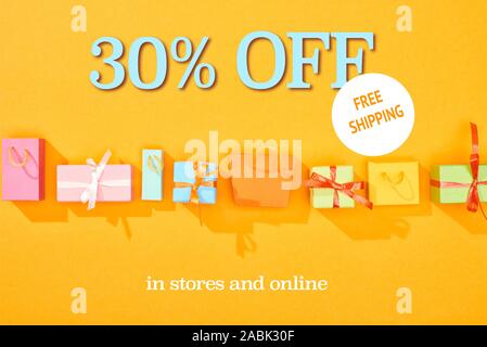 Blick von oben auf die einkaufstaschen und Geschenke auf orangefarbenem Hintergrund mit 30 Prozent weg vom Verkauf Abbildung: Stockfoto