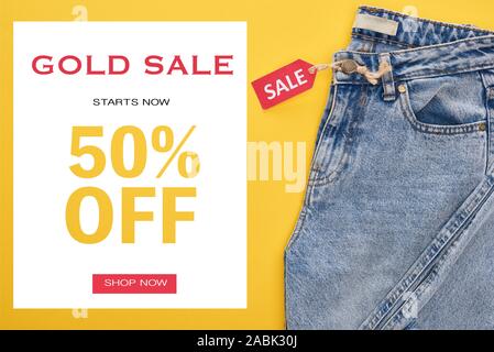 Blick von oben auf die Jeans mit Verkauf Label auf gelben Hintergrund mit gold Verkauf 50 Prozent aus Abbildung Stockfoto