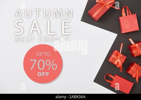 Blick von oben auf die roten Geschenkboxen und Einkaufstaschen auf weißen und schwarzen Hintergrund mit bis zu 70 Prozent aus Herbst verkauf Abbildung: Stockfoto