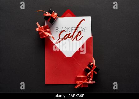 Blick von oben auf die Karte mit schwarzer Freitag verkauf Illustration in roten Umschlag in der Nähe von präsentiert auf schwarzem Hintergrund Stockfoto