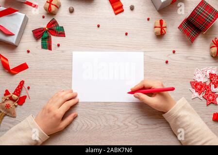 Konzept des Schreibens Weihnachts- und Neujahrsgrüße. Hand hält Stift auf Papier. Freier Speicherplatz für die Begrüßung von Text. Mockup. Ansicht von oben Zusammensetzung, Clos Stockfoto