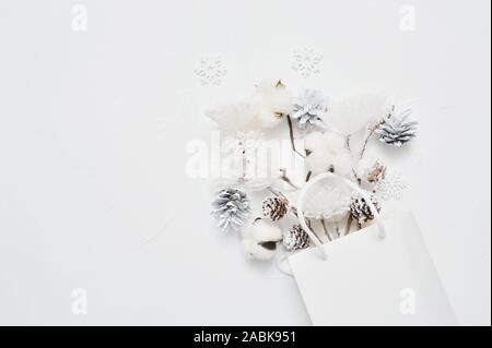 Weihnachten mock up von getrockneten Blumenstrauß aus Baumwolle Blumen, Kegel und Schneeflocken in Weiß-Paket mit Platz für Ihren Text. Grußkarte Design für Poster Stockfoto