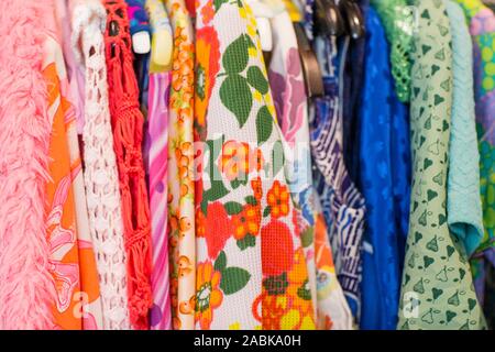 Seitenansicht der einige bunte Vintage Kleidung mit verschiedenen Mustern, Farben und Texturen hängen an einem Rack. Sparsamkeit, Second hand, Kreislaufwirtschaft, recyc Stockfoto