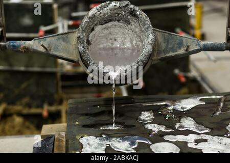 Detail Nahaufnahme der Metall Sandguss Technik, gießt geschmolzenes Aluminium silber farbige Flüssigkeit in eine Form in einem industriellen Umfeld, Workshop s Stockfoto