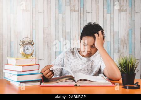 Betonte Student Learning hart mit Büchern in Prüfungen Vorbereitung überwältigt fühlen, während sein Kopf wegen der niedrigen und erschöpft Stockfoto