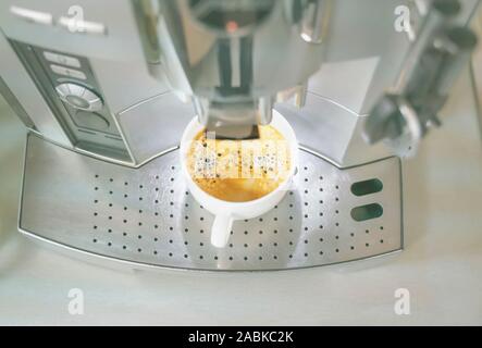 Automatischer Filter Kaffeemaschine abfüllen eine Tasse köstlichen warmen duftenden Kaffee in eine weiße Keramik Tasse. Kaffee gesättigte Farbe und Magic aroma Res Stockfoto