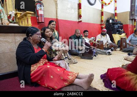 Eine Gruppe von frommen Hindus singen Gebete während der Feier der Kahl Bhairav Jiyanthi, ein Urlaub, eine Form des Gottes Shiva. In Queens, New York City. Stockfoto