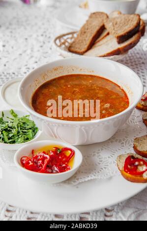 Tomatensuppe mit Pfeffer, Petersilie Gewürze in eine weiße Platte in einem Restaurant mit einer Reihe von Häppchen serviert. Close Up. Stockfoto