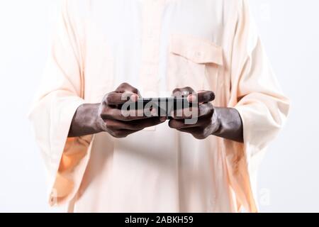 Afrikanischer Mann mit Smartphone und tragen traditioinal Sudan Kleidung auf weißem Hintergrund Stockfoto